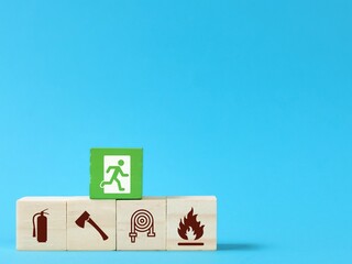 Wooden blocks with fire safety exit icons isolated on blue background. Fire safety protection concept.