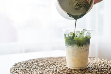 Ice macha green milk tea latte pouring green tea in glass from bowl and green tea grinder with copy space for text. - obrazy, fototapety, plakaty