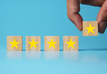 A picture of hand giving 5 star rating using wooden block on blue background