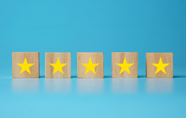 A picture of star at wooden block on blue background. Giving rating concept