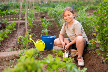 Portrait of a young girl working on a small home farm digging ground in a vegetable garden