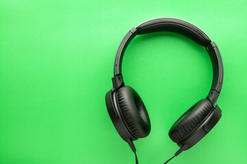 Black wired Headphones on a green background. Entertainment concept