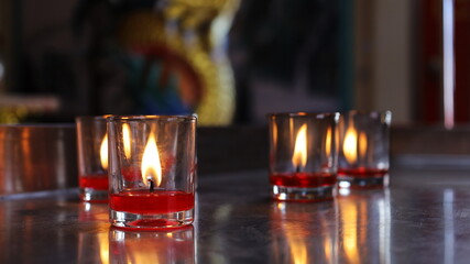 Candle in a glass. Light a red candle in a clear glass to worship the gods in a Chinese shrine. Close focus and select content
