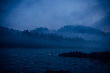 Blue haze, mystical misty morning. Fantastic landscape, thick fog over a mountain river at dusk.