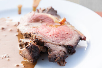 The medium-rare cooked meat with pepper gravy on the white plate