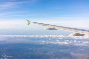 Fototapeta premium View from the airplane window at a beautiful blue sunrise and the airplane wing above the clouds.