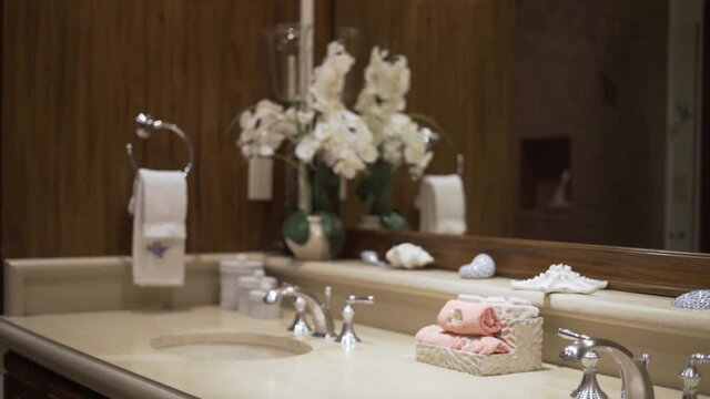 bathroom with faucet towels and soap in front of mirror and orchids