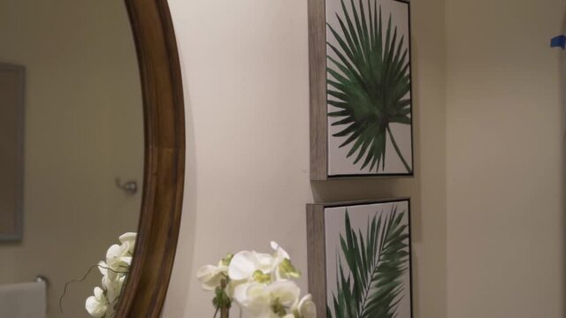 orchid in the bathroom in front of the mirror and pictures of tropical leaves