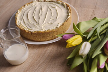 Banana homemade cake, a congratulatory bouquet of flowers and a jug of milk on the table.