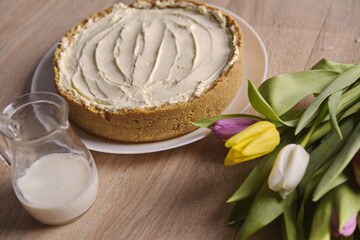 Banana homemade cake, a congratulatory bouquet of flowers and a jug of milk on the table.