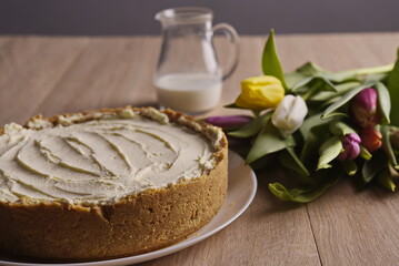 Banana homemade cake, a congratulatory bouquet of flowers and a jug of milk on the table.