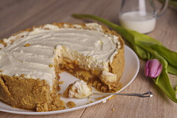 A piece of cake, a jug of milk, and a tulip are spread out on the table.