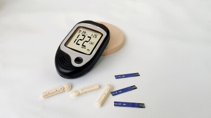 blood glucose meter high blood sugar on a wooden stand, blood needle, lancet and test strip on a...