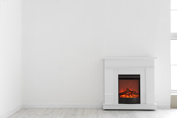 Stylish fireplace near light wall in room - obrazy, fototapety, plakaty