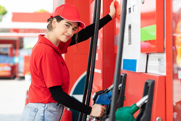 portrait young woman worker holding petrol hose and choosing gasoline at the gas station