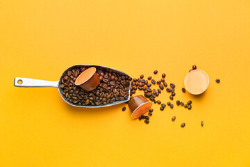Coffee capsules and scoop with beans on color background