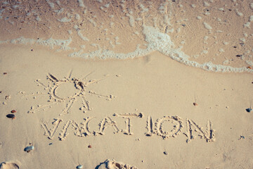 Inscription vacation with shape of sun and incoming sea wave on sand at beach. Summer time