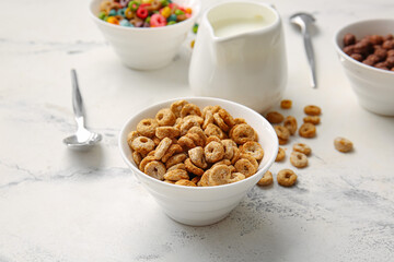Bowls with different cereals and milk on light background