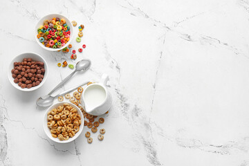 Bowls with different cereals and milk on light background