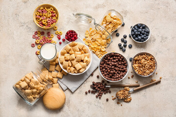 Different cereals, milk and berries on light background