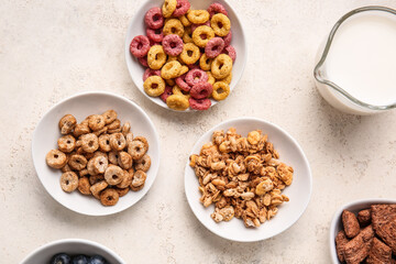 Bowls with different cereals and milk on light background