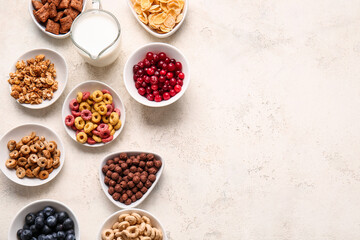Obraz na płótnie Canvas Bowls with different cereals, berries and milk on light background