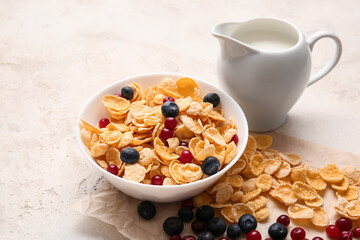 Bowl with tasty corn flakes, milk and berries on light background, closeup