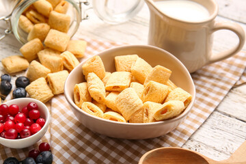 Bowls with tasty corn pillows, milk and berries on light wooden background, closeup