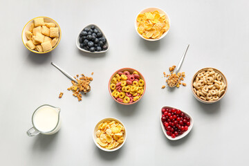Composition with different cereals, berries and milk on light background