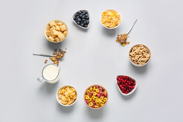 Frame made of different cereals, berries and milk on light background