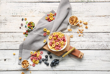 Bowls with different cereals and blueberry on light wooden background