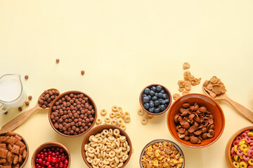 Bowls with different cereals, milk and berries on color background