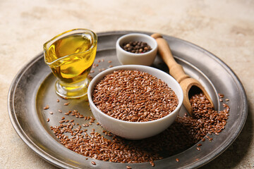 Tray with flax seeds, oil and peppercorns on light background, closeup