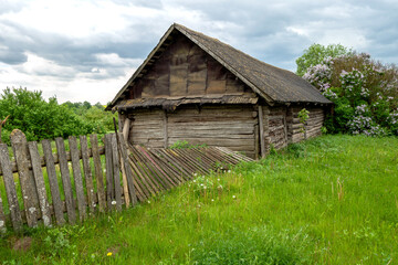 Old wooden building in a village with a fallen fence