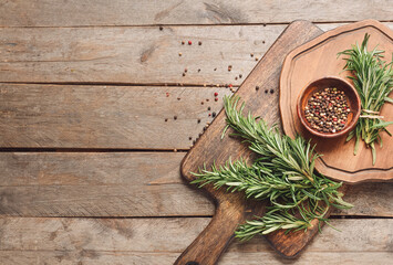 Composition with fresh rosemary and peppercorns on wooden background
