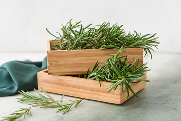 Boxes with fresh rosemary on color background