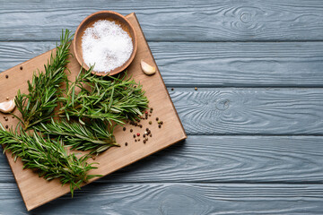 Board with fresh rosemary and spices on dark wooden background