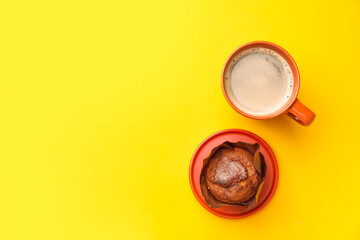 Cup of freshly brewed coffee and muffin on color background