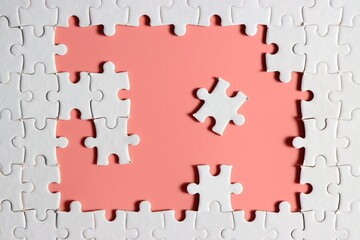 incomplete white jigsaw puzzle with plain pink background for your content