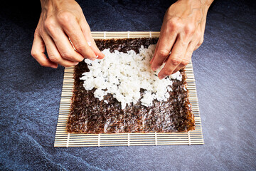 Female chef preparing rice on nori for delicious sushi. Asian food concept