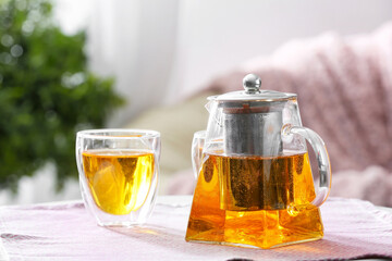 Teapot and cups of hot beverage on table in room