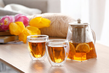 Teapot and cups of hot beverage on table in room