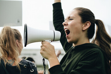 Female activist shouting on a megaphone - obrazy, fototapety, plakaty