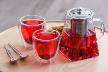 Teapot and cups of hot beverage on table in room