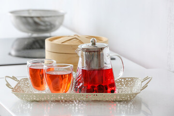Teapot and cups of hot beverage on table in room