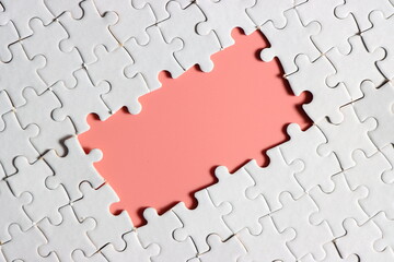 disassemble incomplete white jigsaw puzzle pieces with plain pink empty space.