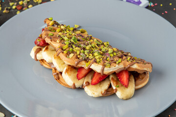 sandwich waffles with banana, strawberry and chocolate and pistachio on top