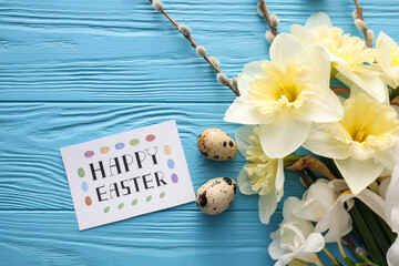 Beautiful flowers, quail eggs and card with text HAPPY EASTER on color wooden background, closeup