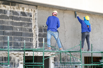 Fototapeta premium Plasterers using and operating sprayer mortar equipment machine for spraying mortar concrete cover brick wall and plastering for the decoration finishing work at the construction site