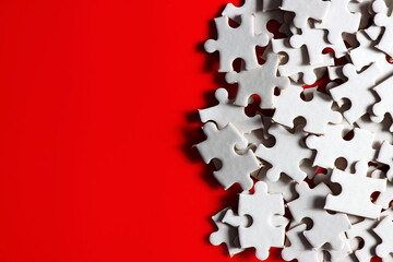 disassemble incomplete white jigsaw puzzle pieces and plain red background.